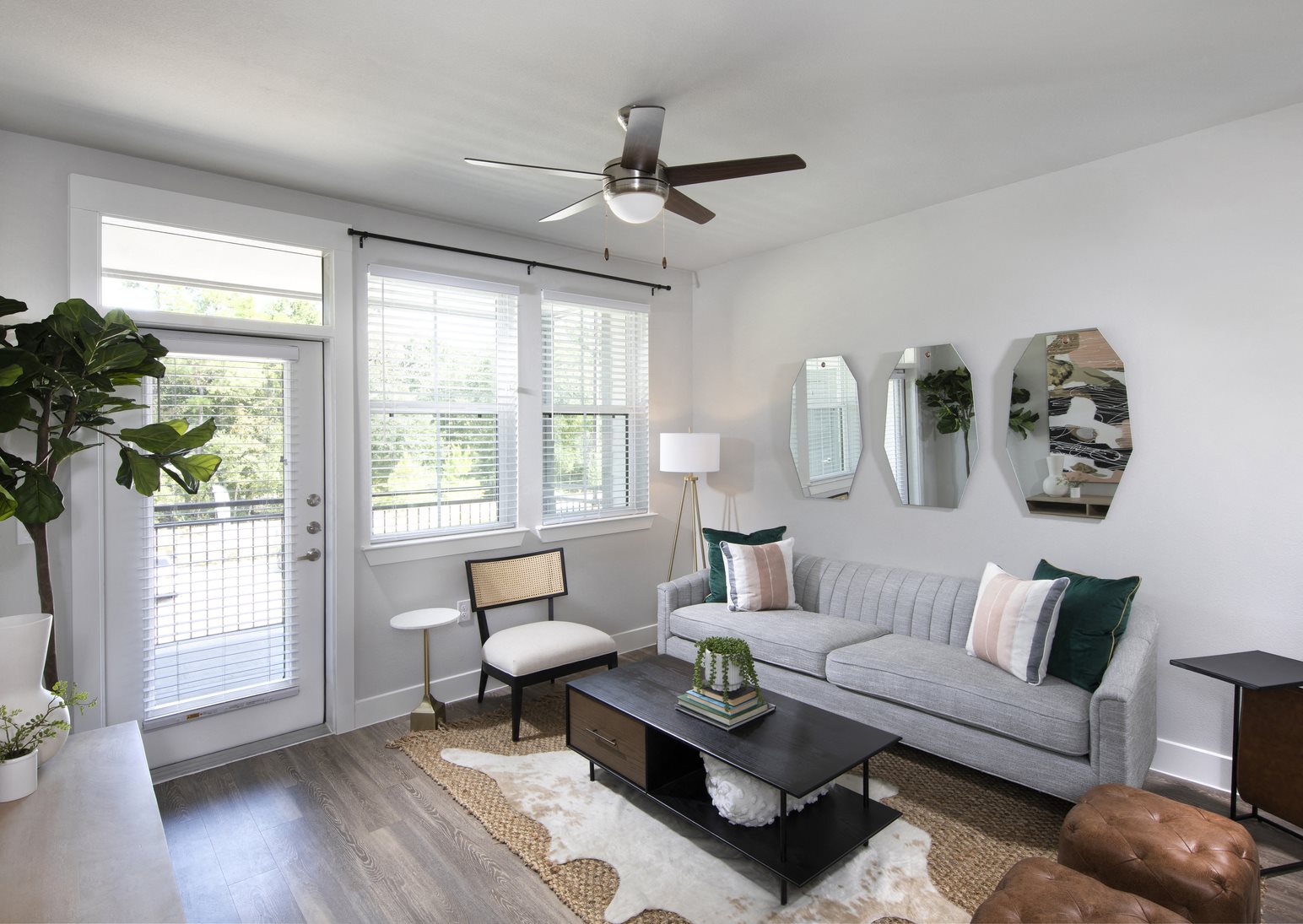 a living room with a ceiling fan and door that opens to a patio at a senior apartment community